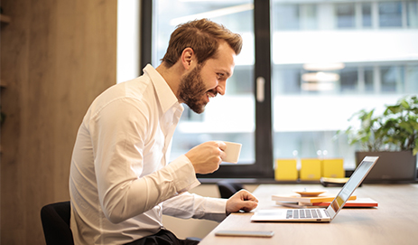 Man zit achter laptop aan bureau