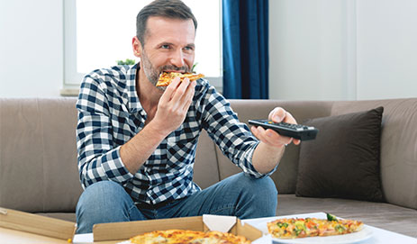 Man eet pizza voor de tv