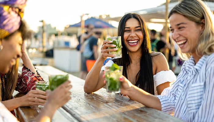 Lachende vrouwen met drankjes aan picknicktafel