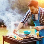 Man braad vlees op barbecue