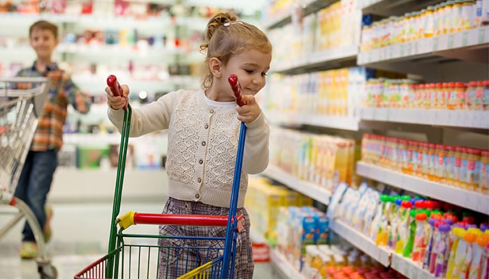 Meisje met klein boodschappenwagentje in supermarkt