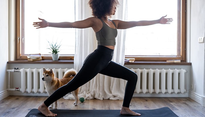 Vrouw in yogapose op matje thuis