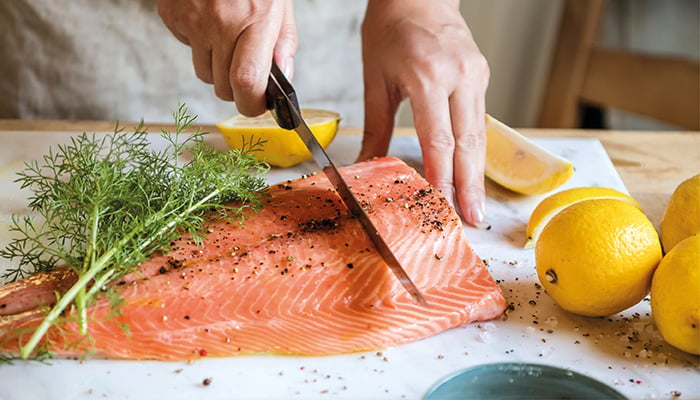 Zalm wordt gesneden op snijplank