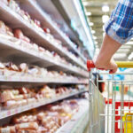 Vrouw loopt door supermarkt met winkelwagen