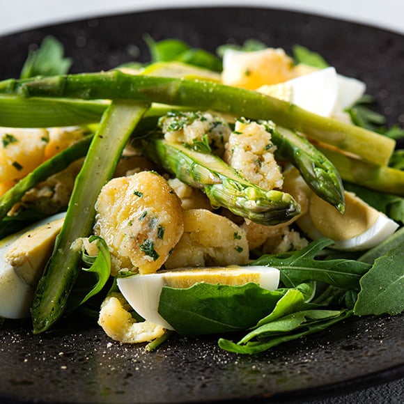 Bord met salade van rucola, groene asperges, aardappel en gekookt ei