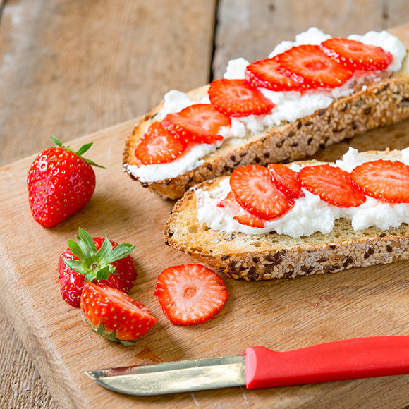 Twee stukken toast met huttenkase en aardbeien