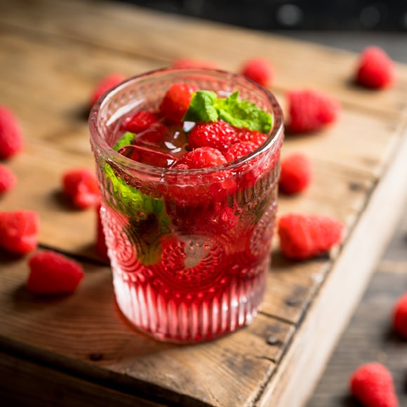 Glas met frambozendrankje op een snijplank