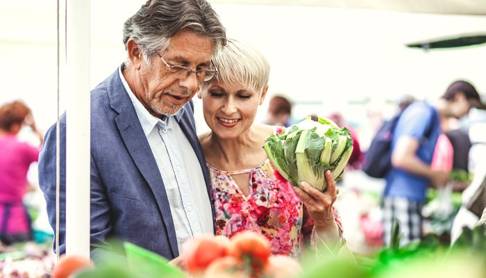 Man en vrouw kiezen groenten op markt