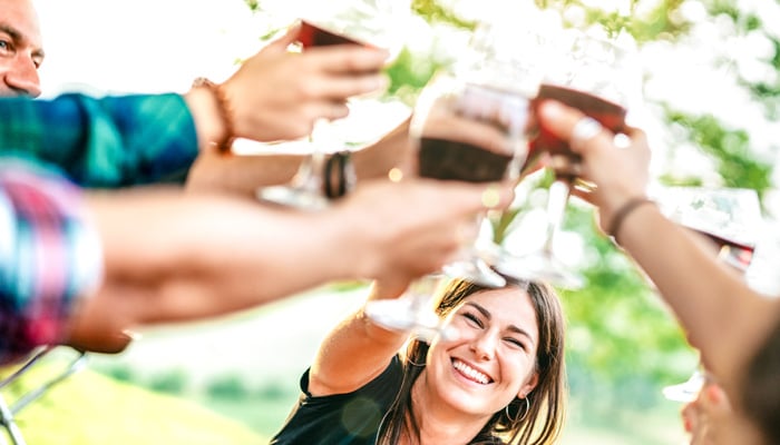 Vrouw proost in groep met glas wijn