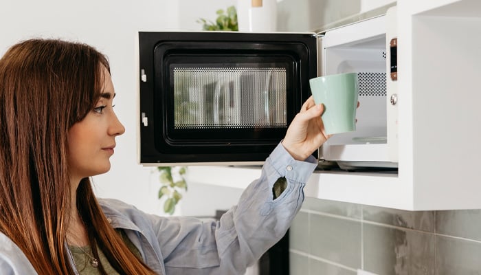 Meisje zet kopje in magnetron