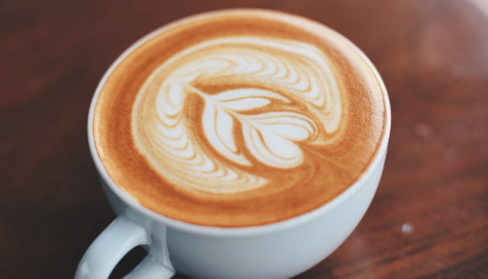 Kopje koffie met bloemmotief in de opgeschuimde melk