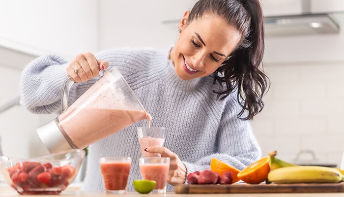 Vrouw maakt smoothies van fruit in de blender