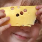 Meisje houdt plak kaas voor haar gezicht