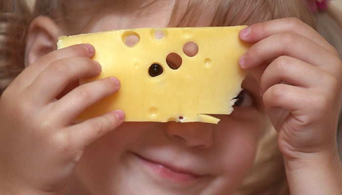 Meisje houdt plak kaas voor haar gezicht