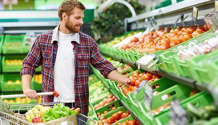 Man doet boodschappen. Zijn winkelwagen zit vol groente.