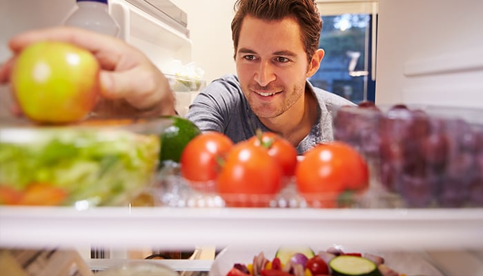 Man pakt fruit uit koelkast