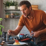 Man doet saus op spaghetti